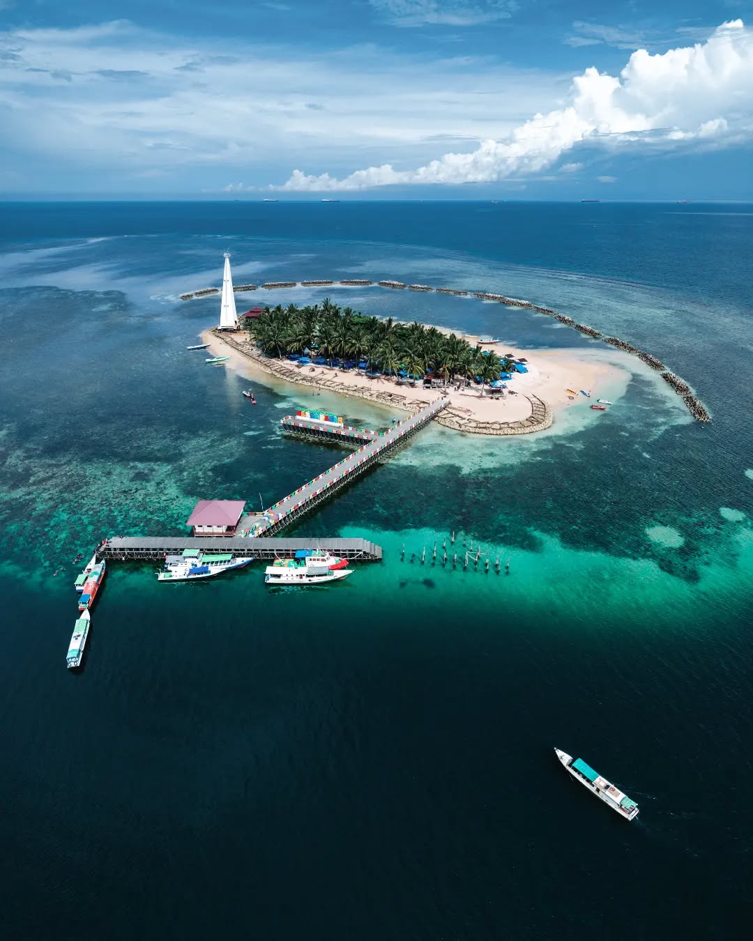 Panorama Pulau Beras Basah dengan pasir putih, laut biru, dan mercusuar tinggi jadi daya tarik visual utama.