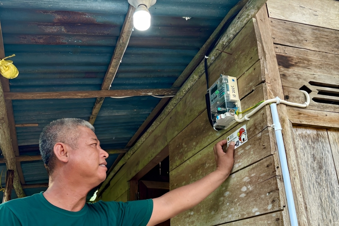 Ruslan, warga Musi Banyuasin, tersenyum bahagia di rumahnya yang kini terang berkat Program BPBL dari Kementerian ESDM dan PLN.