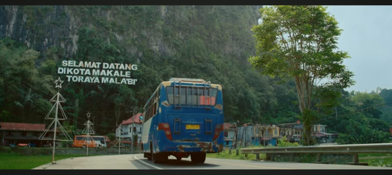 Guru Angkasa berdiri di tengah lanskap desa Olon yang berkabut, menatap langit dengan sorot mata penuh harapan &mdash; visualisasi sempurna dari perjuangan dan pelarian batin.