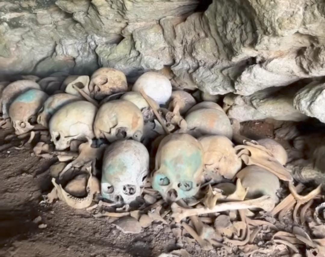 Pemandangan mulut Goa Tengkorak Kasungai berlatar perbukitan hijau&mdash;pesona alam misterius yang memikat mata.