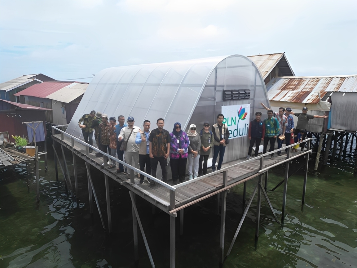 Sejumlah perwakilan PLN dan masyarakat setempat berfoto di depan fasilitas pengering rumput laut bertenaga surya yang dibangun melalui program PLN Peduli di kawasan pesisir.