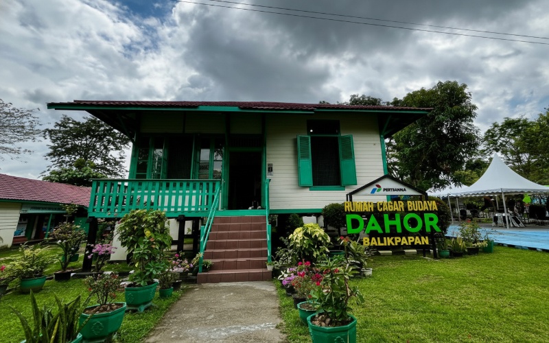 Rumah panggung ulin kolonial Dahor Heritage dengan jendela besar dan suasana hijau yang menghadirkan nuansa nostalgia visual.