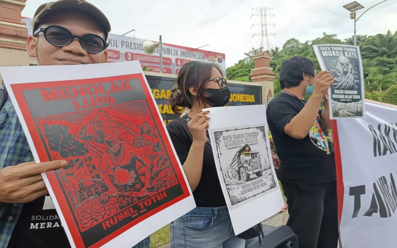 Aksi warga Muara Kate di depan Polda Kaltim membawa spanduk tuntutan, visual dramatis penuh energi solidaritas.