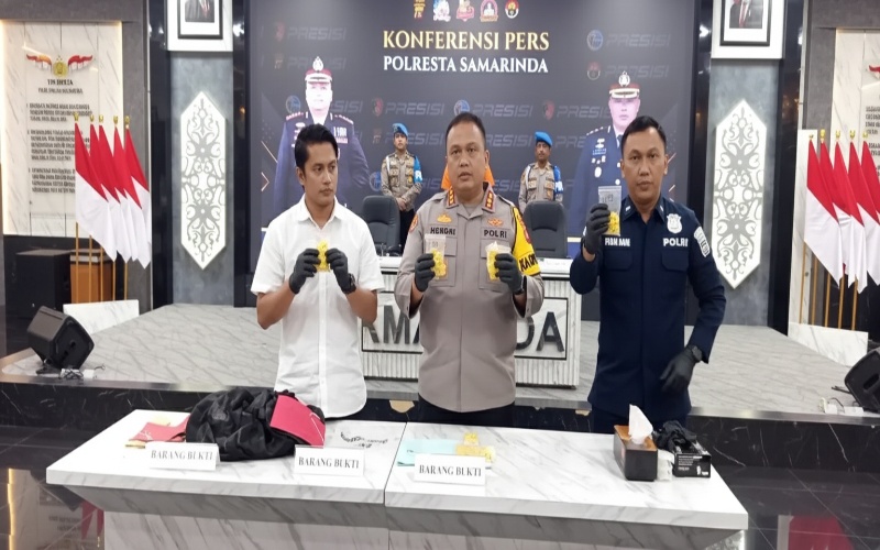 Barang bukti ekstasi logo lebah warna kuning terdisplay di meja rilis kasus, latar logo Polresta Samarinda.