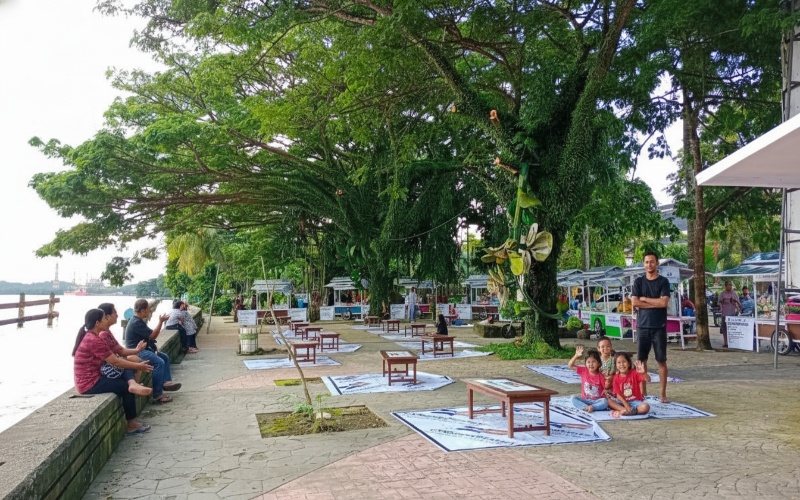 Panorama Taman Tepian Mahakam dengan jalur pedestrian, patung buah raksasa, dan cahaya lampion&mdash;visual yang memikat mata.