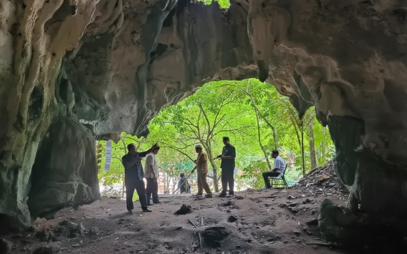 Mulut Gua Tapak Raja dengan cahaya dari lubang atas, menonjolkan stalaktit&ndash;stalagmit sebagai visual hook.