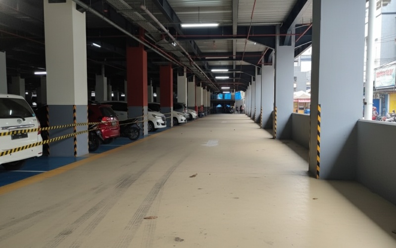 Area parkir Pasar Pagi Samarinda dengan rencana sistem nontunai parking gate&mdash;visual dinamika modernisasi fasilitas publik.