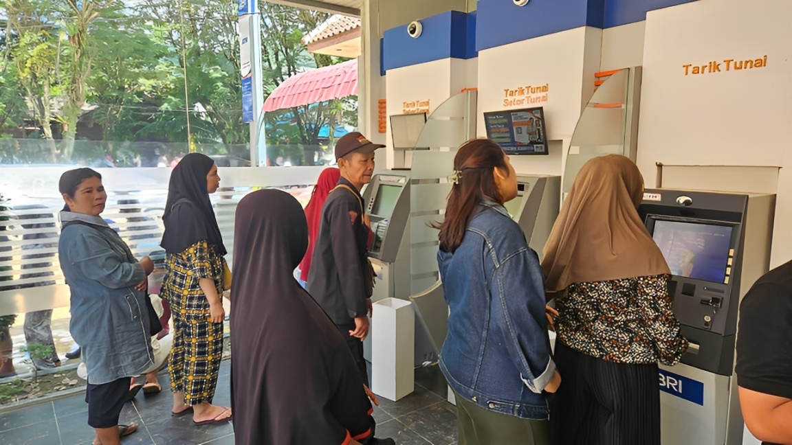 Warga mengantre menggunakan mesin tarik tunai di Galeri e-Banking BRI.