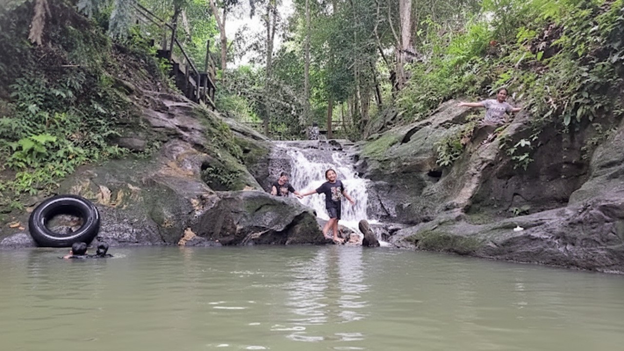 Air Terjun Perjiwa dengan aliran bertingkat di tengah pepohonan hijau, menghadirkan suasana natural yang menenangkan &ndash; visual healing alami.