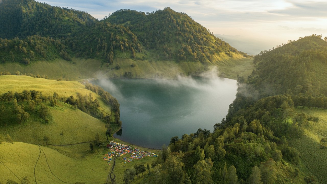 Ranu Kumbolo golden sunrise view dengan kabut tipis dan pantulan cahaya lembut sebagai hook visual.