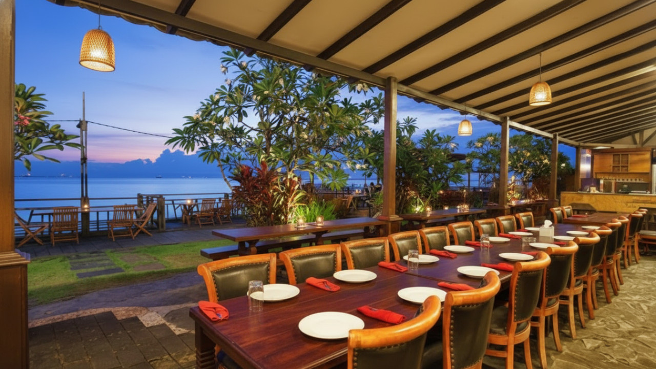 Pemandangan meja makan di tepi pantai Ocean&rsquo;s Resto dengan seafood segar dan panorama laut sebagai latar yang memikat.