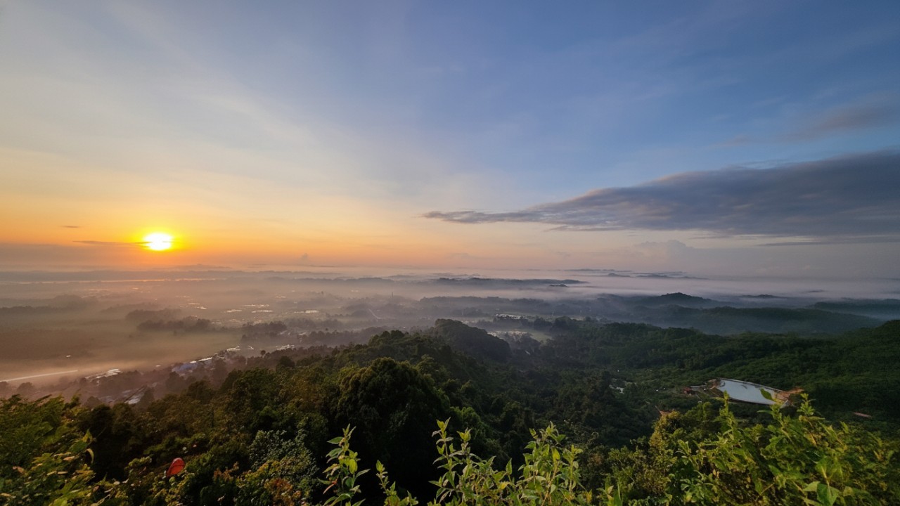 Panorama sunrise dari Puncak Bukit Biru dengan hamparan lembah, hutan hijau, dan kota Tenggarong di kejauhan.