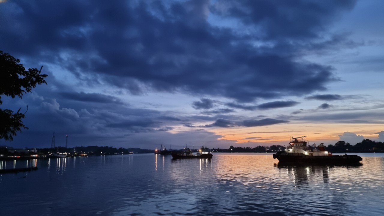 Panorama malam Tepian Sungai Segah dengan lampu hias, jalur pedestrian, dan warga menikmati suasana sungai.