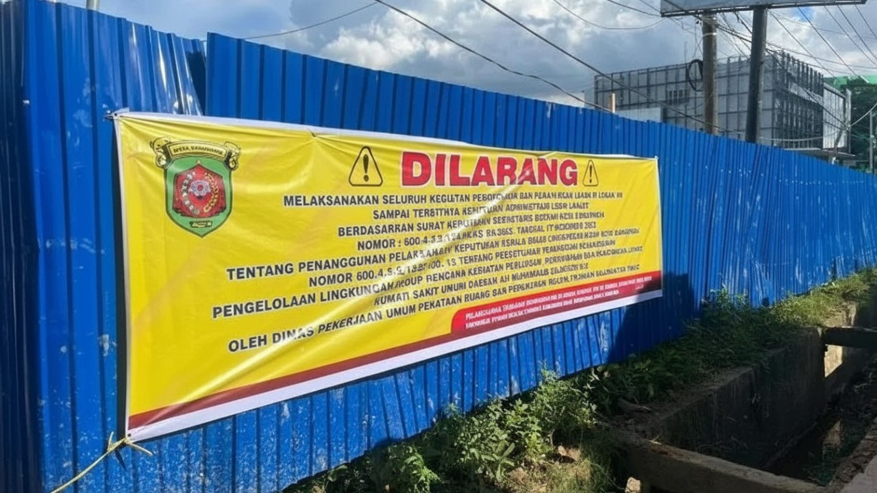 Spanduk larangan terpasang di pagar proyek pematangan lahan RSUD AMS II Samarinda, menandai penghentian sementara aktivitas pengurukan.
