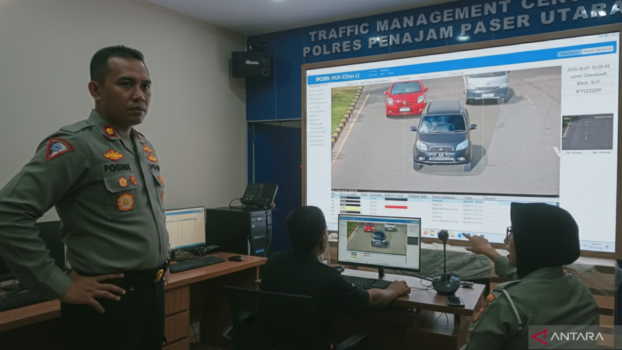 Kamera ETLE statis memantau lalu lintas di titik ramai Penajam, simbol pengawasan adil dan keselamatan bersama.