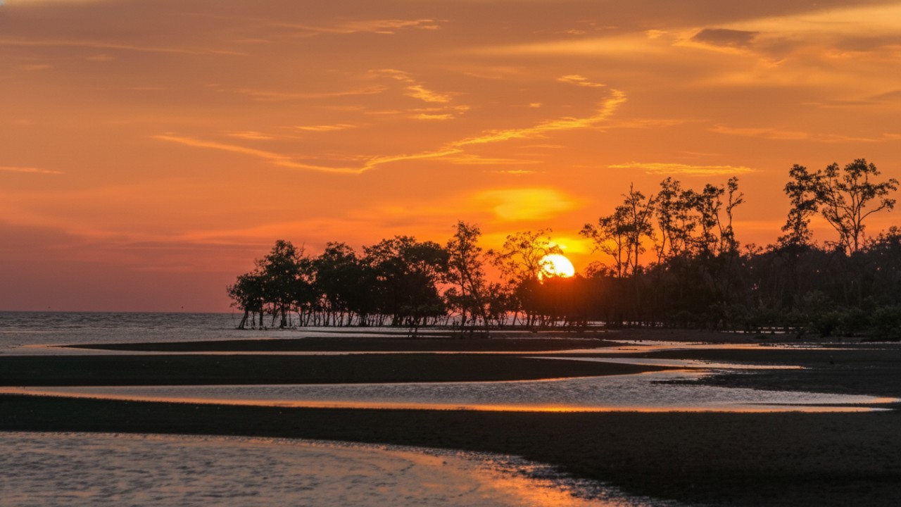 Suasana senja di Pantai Kemala Balikpapan dengan pasir bersih dan pengunjung bersantai menikmati laut.