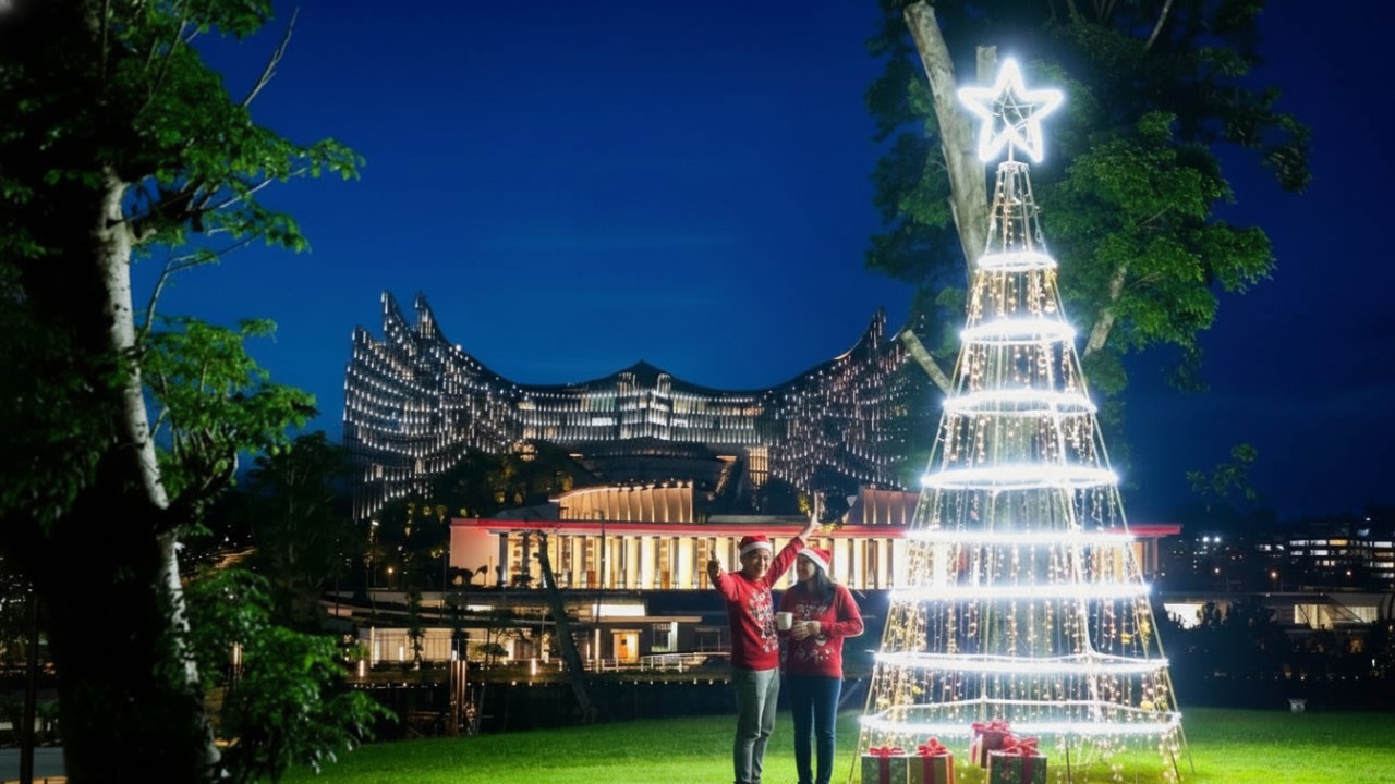 Pengunjung mengabadikan momen di depan pohon Natal dengan latar kawasan Ibu Kota Nusantara (IKN).