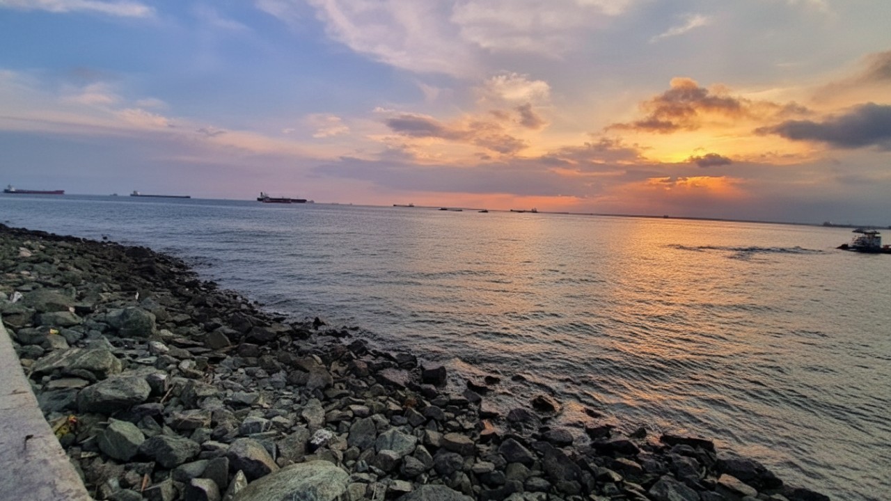 Suasana sunset di Pantai Melawai Balikpapan dengan siluet kapal laut dan pengunjung menikmati senja.