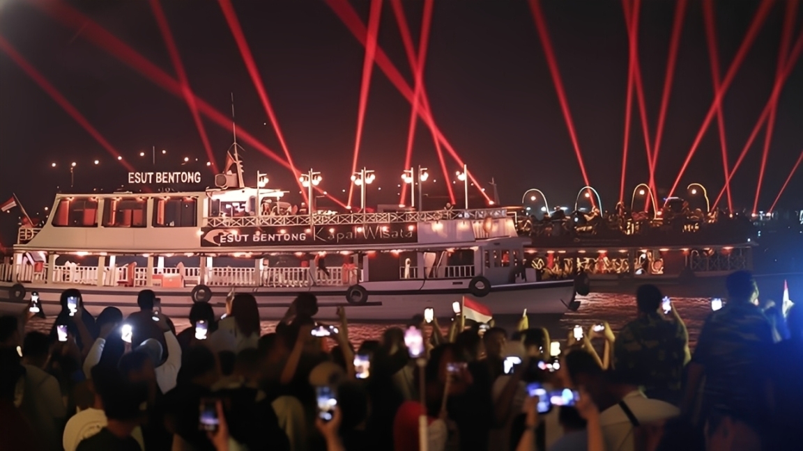 Suasana warga menyaksikan pertunjukan light show yang melintas di Sungai Mahakam, Samarinda, Kamis (1 Januari 2026).