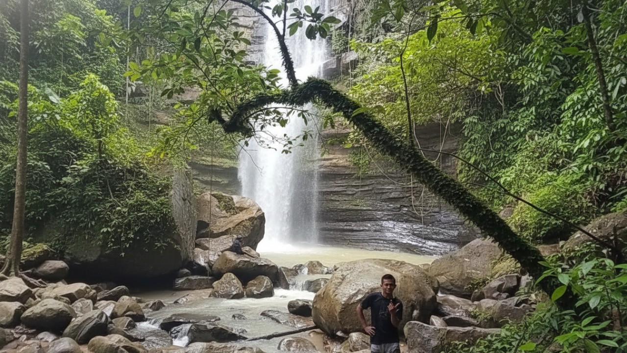 Air Terjun Tembinus dengan aliran deras dan tebing batu berlapis di tengah hutan tropis Sepaku yang masih alami.