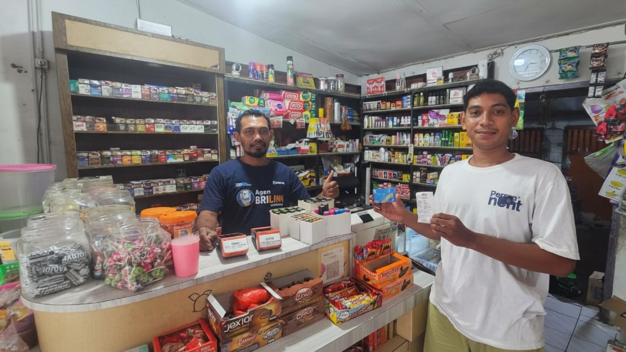 Kamaludin Lahiji (kiri) berfoto bersama warga usai sukses melakukan transaksi di kios BRILink Agen Sorwaru.