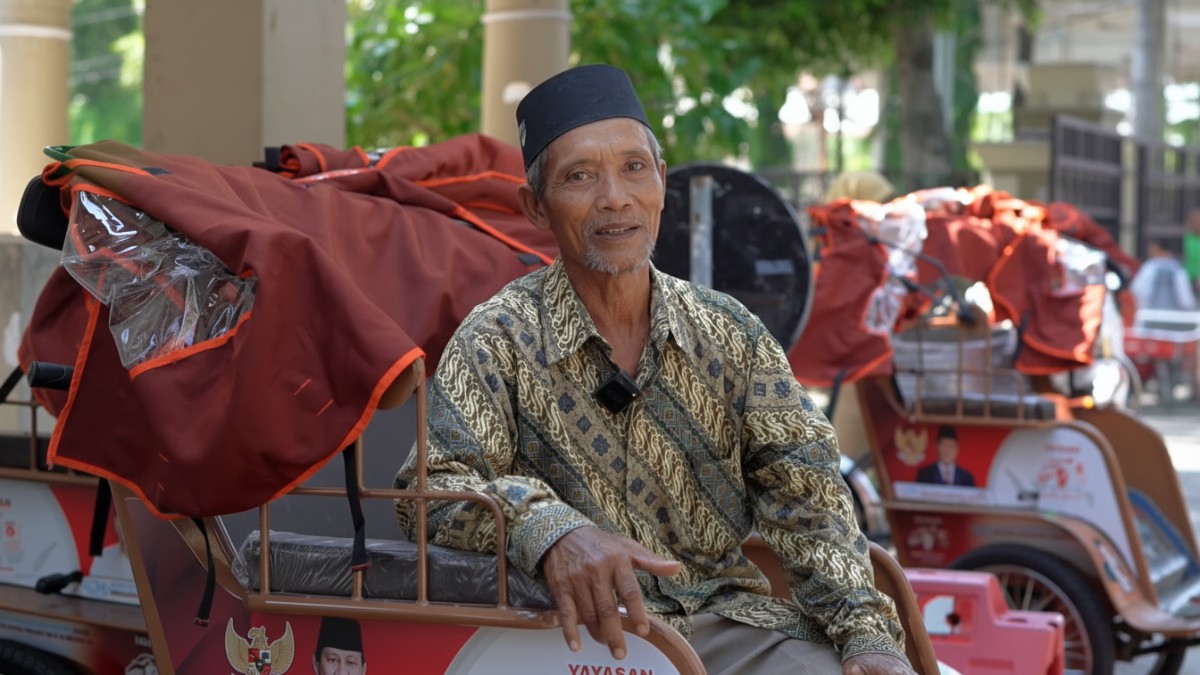 Nawan mencoba becak listrik yang diterimanya dengan bahagia.
