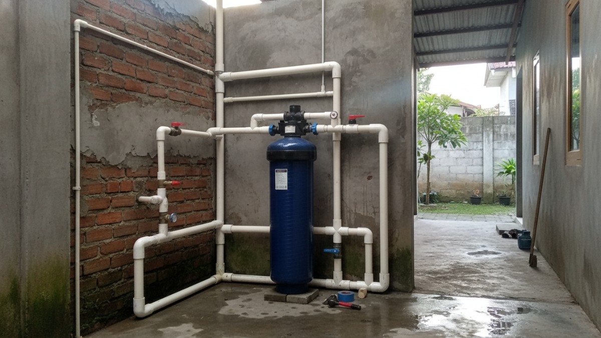 Instalasi filter karbon aktif pada sistem pipa rumah.