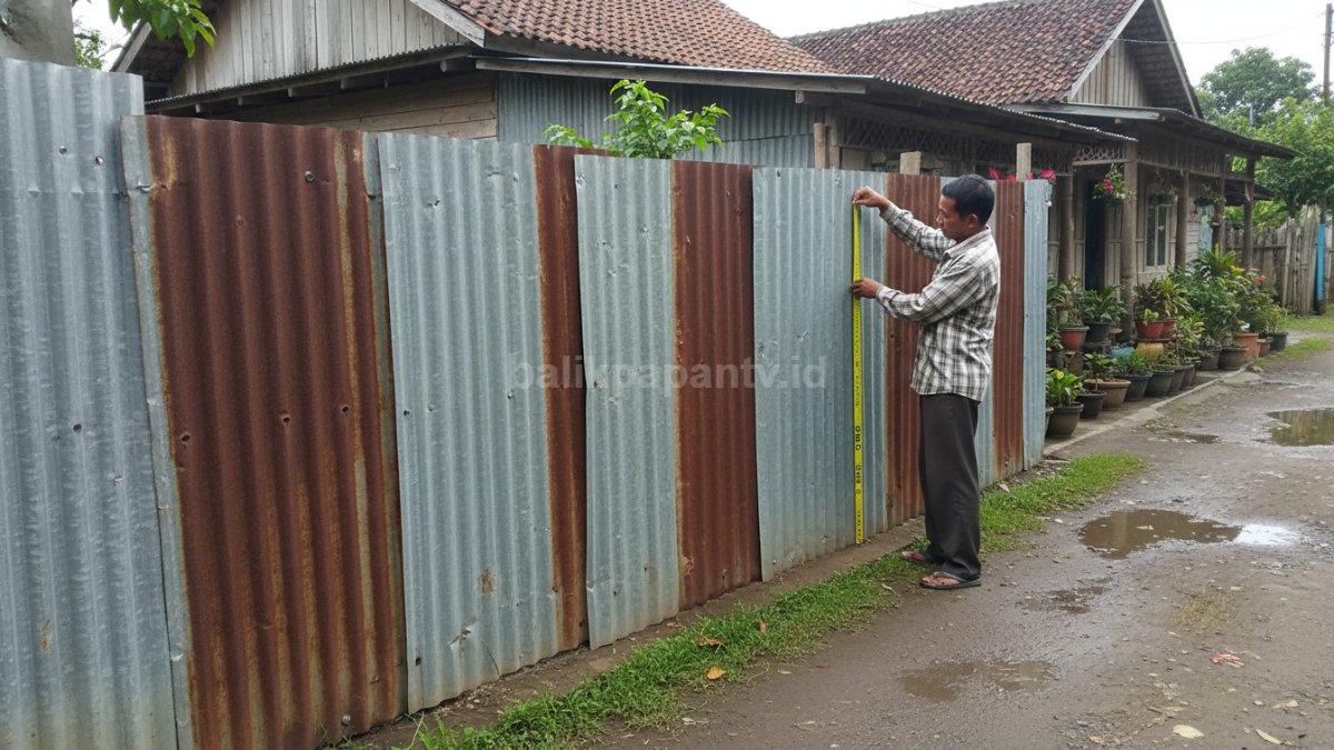 Ilustrasi pengukuran tinggi pagar seng menggunakan meteran di depan rumah &mdash; menggambarkan standar ukuran