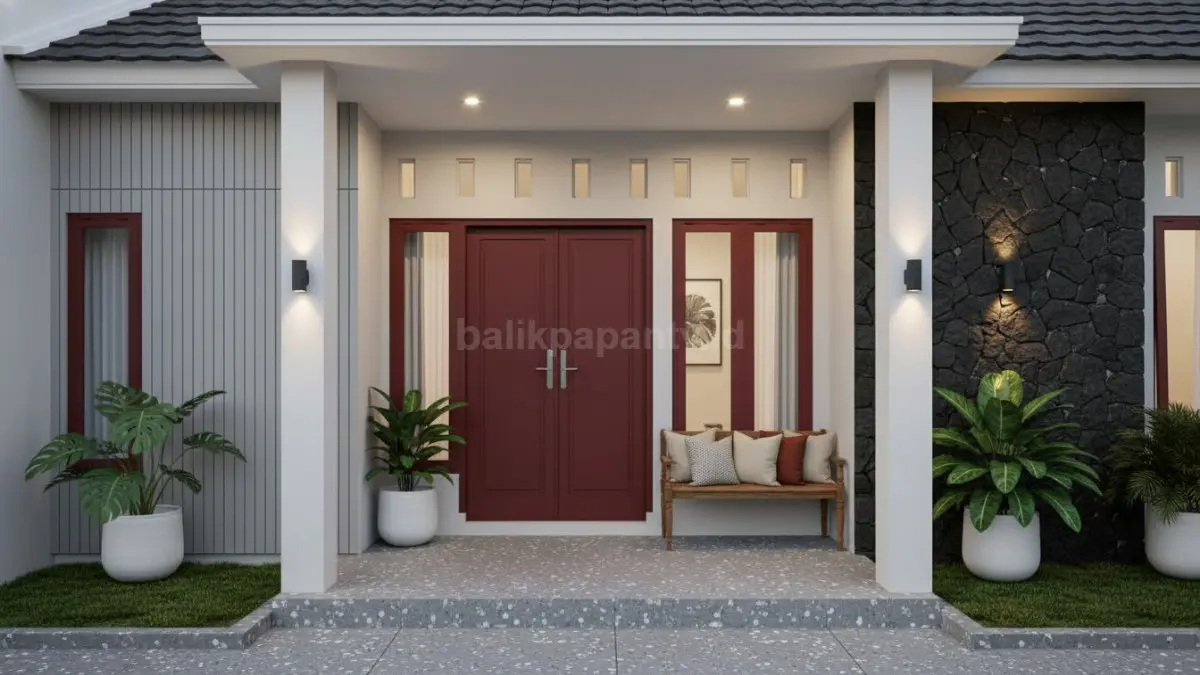 Pintu merah marun dikombinasi pilar putih membuat fasad terlihat berani tanpa berlebihan.
