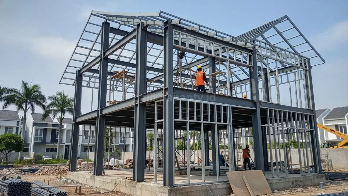 Tampilan rangka rumah dua lantai menggunakan kombinasi baja WF sebagai kolom utama dan baja ringan pada bagian atap, terlihat proses konstruksi yang rapi dan presisi di lokasi proyek.