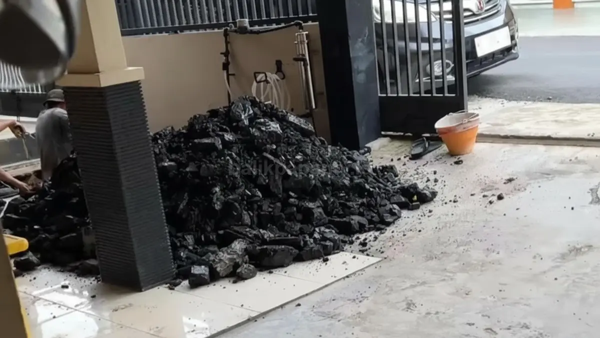 Lubang galian septic tank dengan tumpukan batu hitam pekat di sampingnya