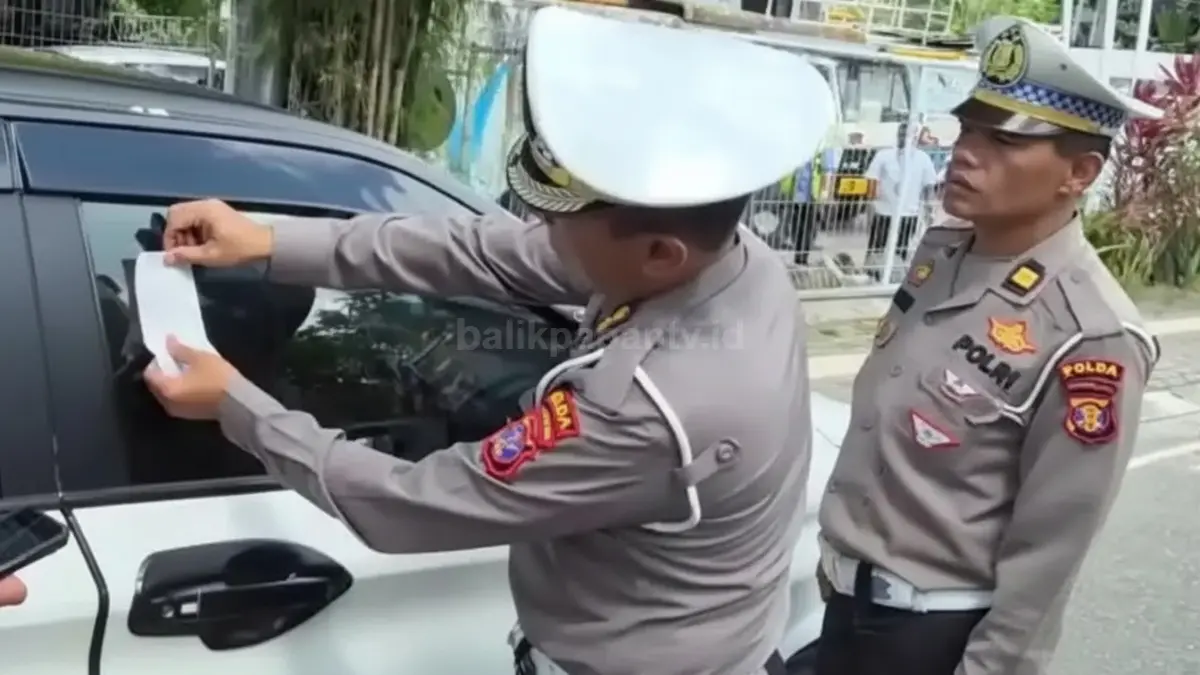 Petugas menempelkan barcode ETLE pada kendaraan pelanggar.