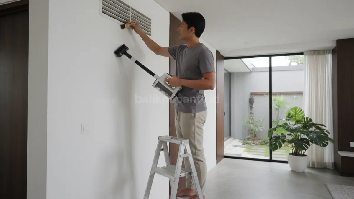 Membersihkan ventilasi memakai vacuum portable dan kuas lembut di rumah minimalis
