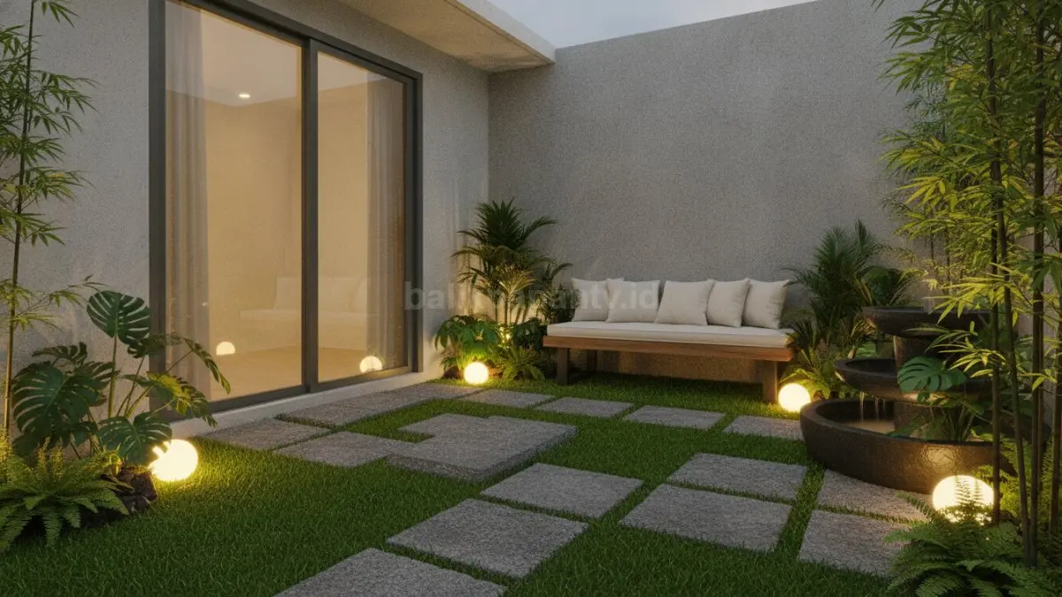 Area teras kecil dengan rumput sintetis, batu alam, dan pencahayaan taman yang hangat.
