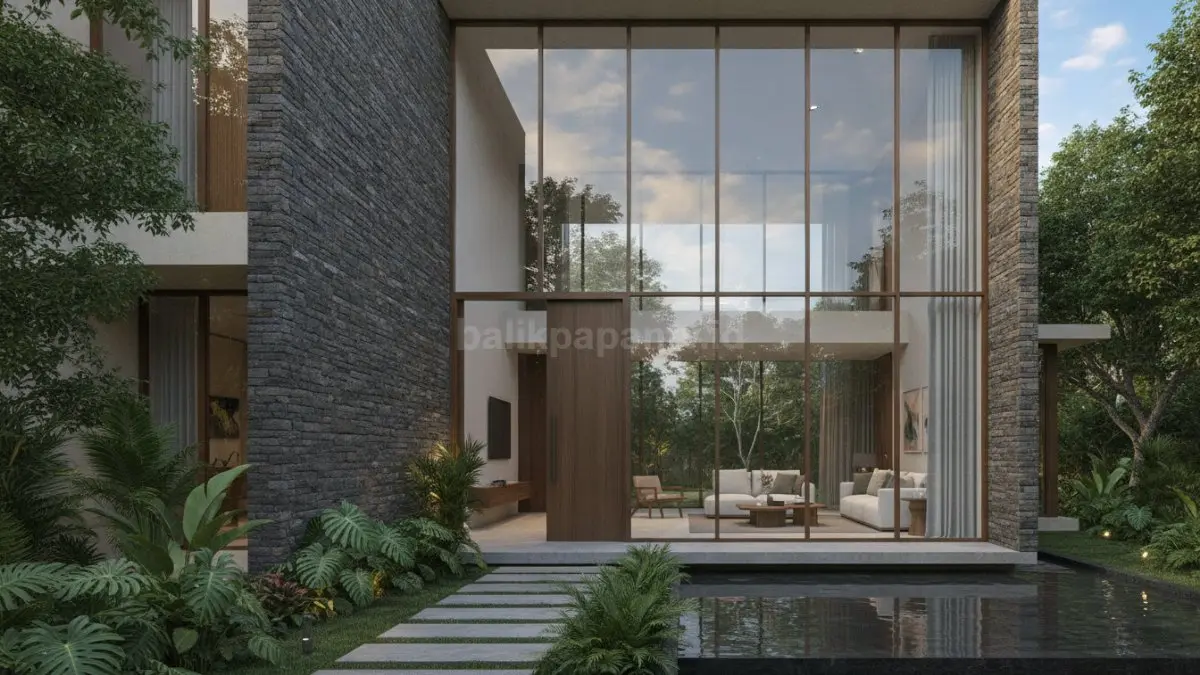 Fasad batu alam dengan aksen kaca besar menghadirkan kekuatan visual sekaligus memaksimalkan cahaya alami pada rumah tropis modern. (BTV/Ai)
