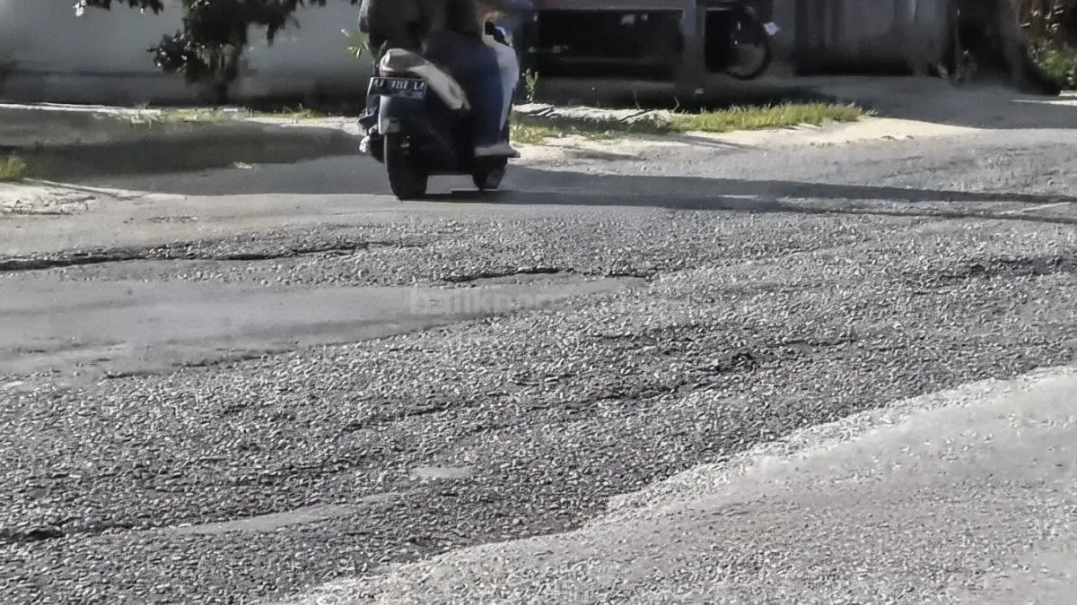 Petugas Dinas PUPR melakukan penambalan darurat pada aspal jalan berlubang di ruas Nenang.