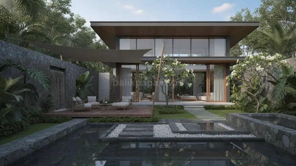 Rumah ala Bali modern dengan taman tropis dan batu alam yang menciptakan suasana sejuk dan nyaman.

