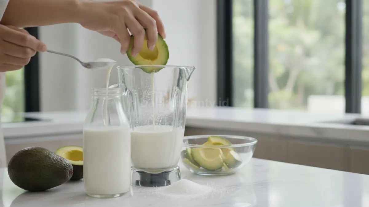 Proses memasukkan alpukat matang, susu, dan gula ke dalam blender sebelum dihaluskan.
