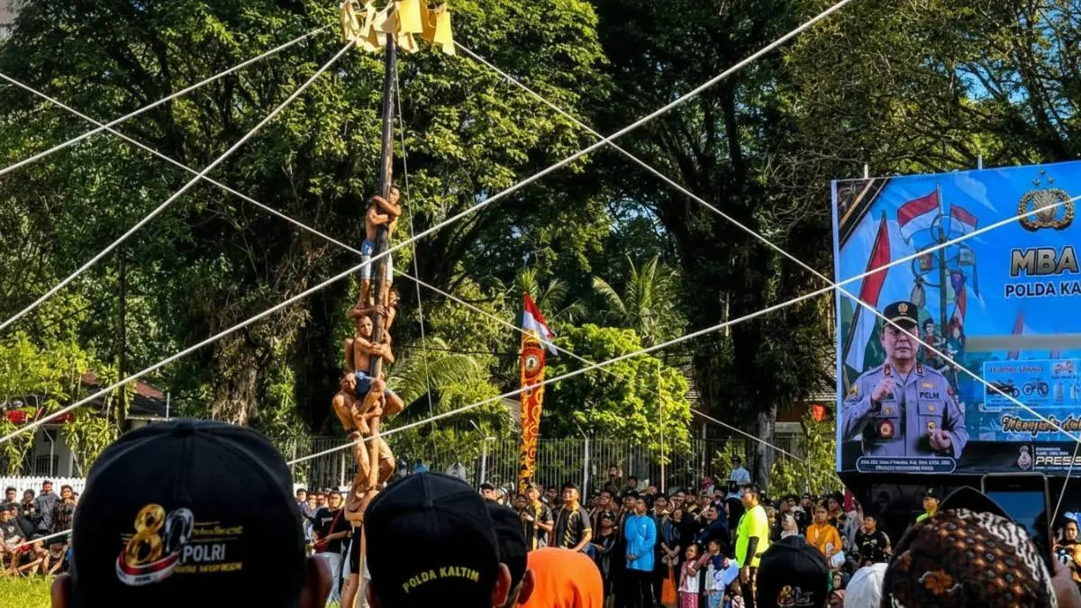 Suasana lomba panjat pinang Hari Bhayangkara ke-80 Polda Kaltim di Lapangan Merdeka Balikpapan yang dipadati peserta dan penonton.