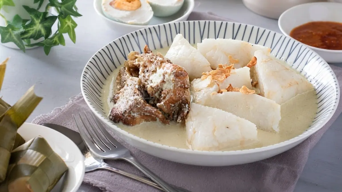 Semangkuk Ketupat Kandangan dengan kuah santan dan ikan haruan panggang, ikon kuliner khas Kalimantan Selatan. (BTV/AI)