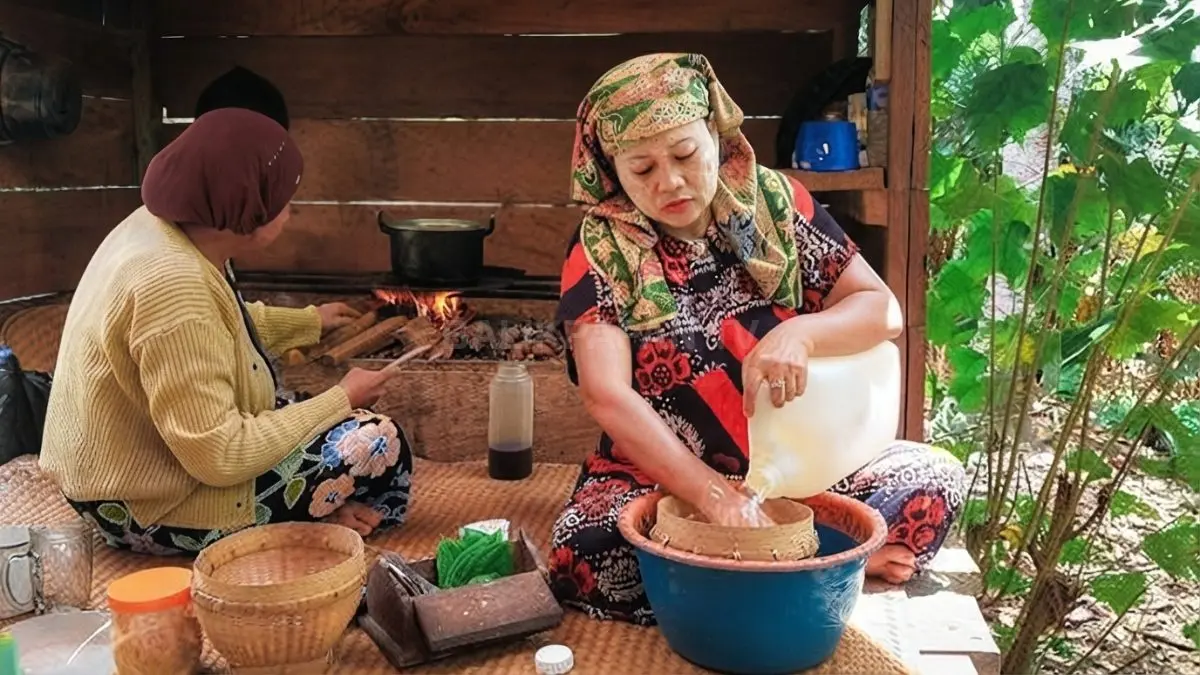 Warga kampung Dayak di Kalimantan memasak menggunakan tungku tradisional sambil menyiapkan sambal tempuyak khas daerah. (BTV/AI)