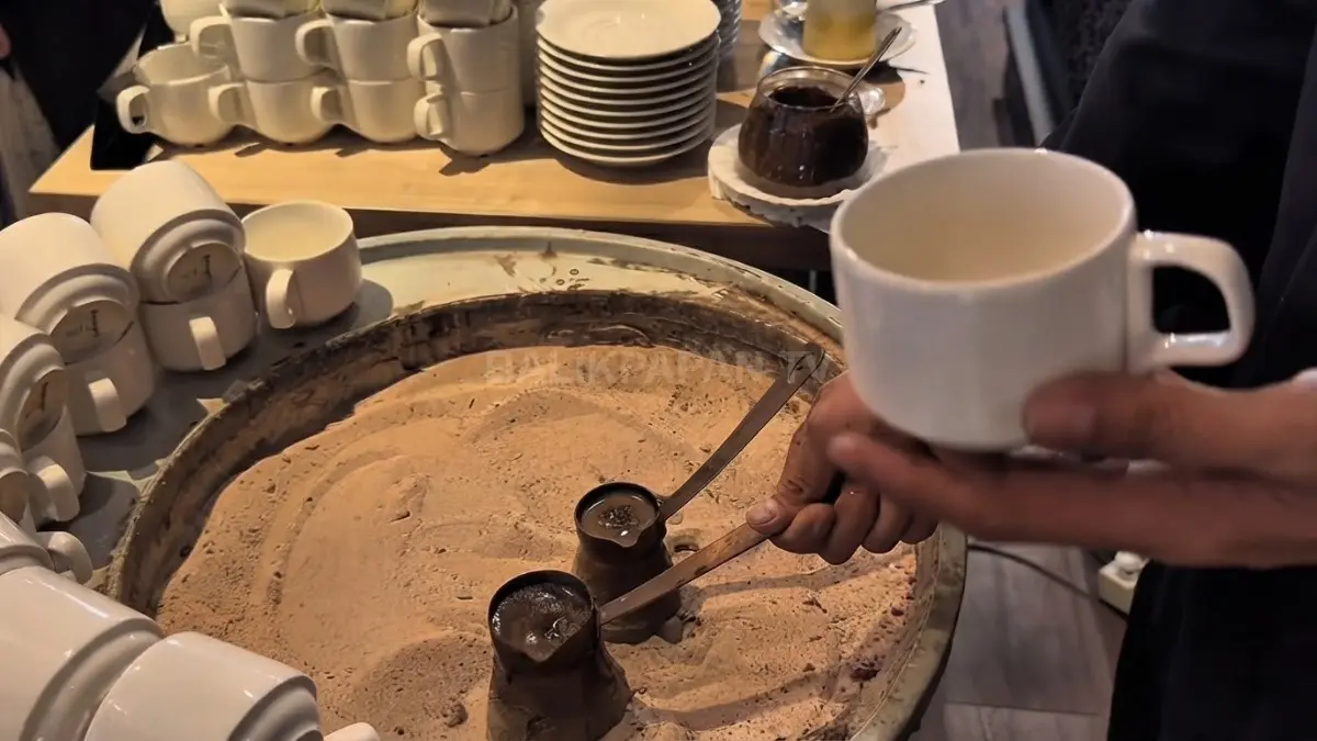 Barista menyiapkan Turkish coffee menggunakan pasir panas di Swiss-Belhotel Balikpapan dengan teko cezve tradisional.