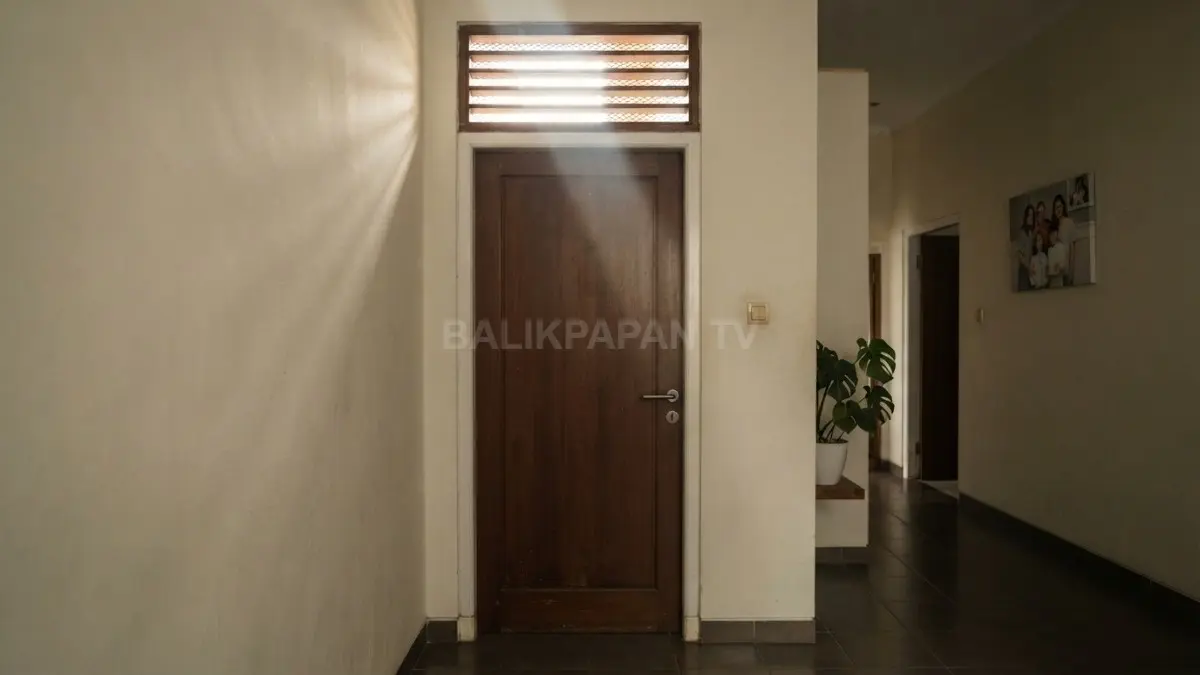 Pintu kamar tidur tertutup dengan cahaya masuk dari ventilasi, menggambarkan pentingnya sirkulasi udara dalam rumah. (BTV/AI)