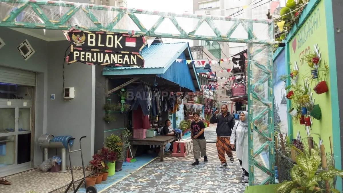 Pengunjung berjalan menyusuri lorong mural Kampung Pinisi yang menghadirkan suasana kampung pesisir penuh warna. (BTV/AI)