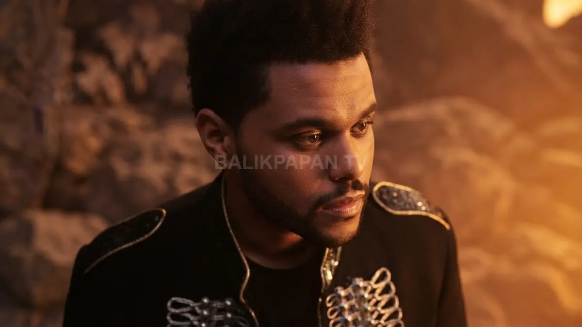 Potret misterius The Weeknd tampil karismatik dalam balutan busana dramatis bernuansa hangat dan misterius. (BTV/Ai)