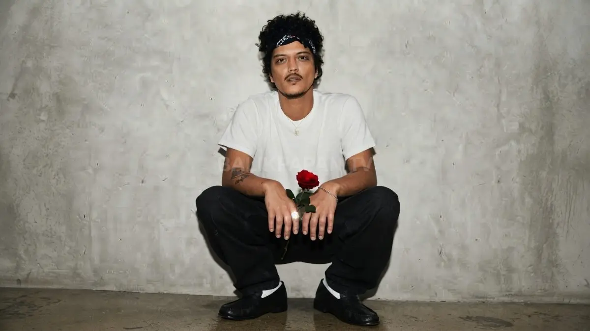 Potret santai Bruno Mars memegang mawar merah tampil memesona dengan gaya kasual yang santai. (BTV/Ai)