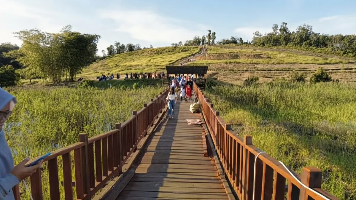 Jembatan kayu membentang menuju area perairan Danau Tanjung Sarai yang masih dalam tahap pengembangan.