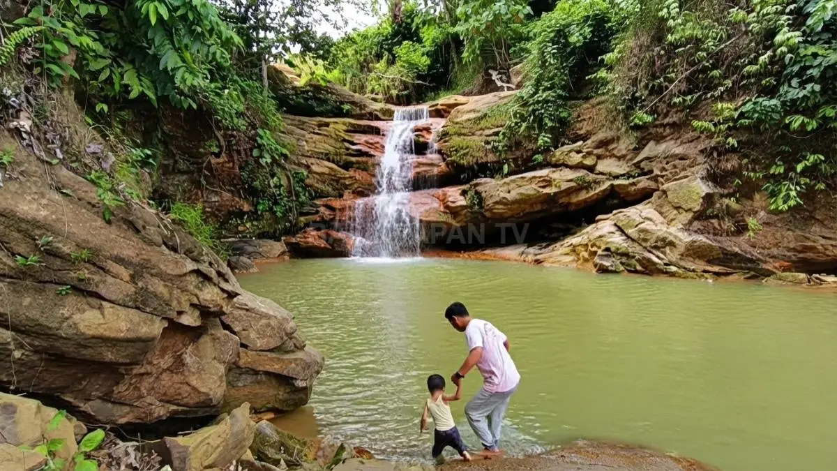 Pengunjung menikmati suasana Air Terjun Berambai sambil bermain air dan merasakan kesejukan kawasan hutan.