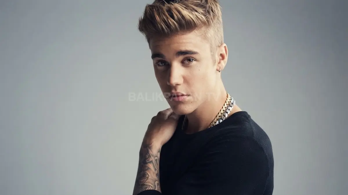 Potret memesona Justin Bieber dengan tatanan rambut pirang dan kaus hitam yang memancarkan pesona karismatik. (BTV/Ai)