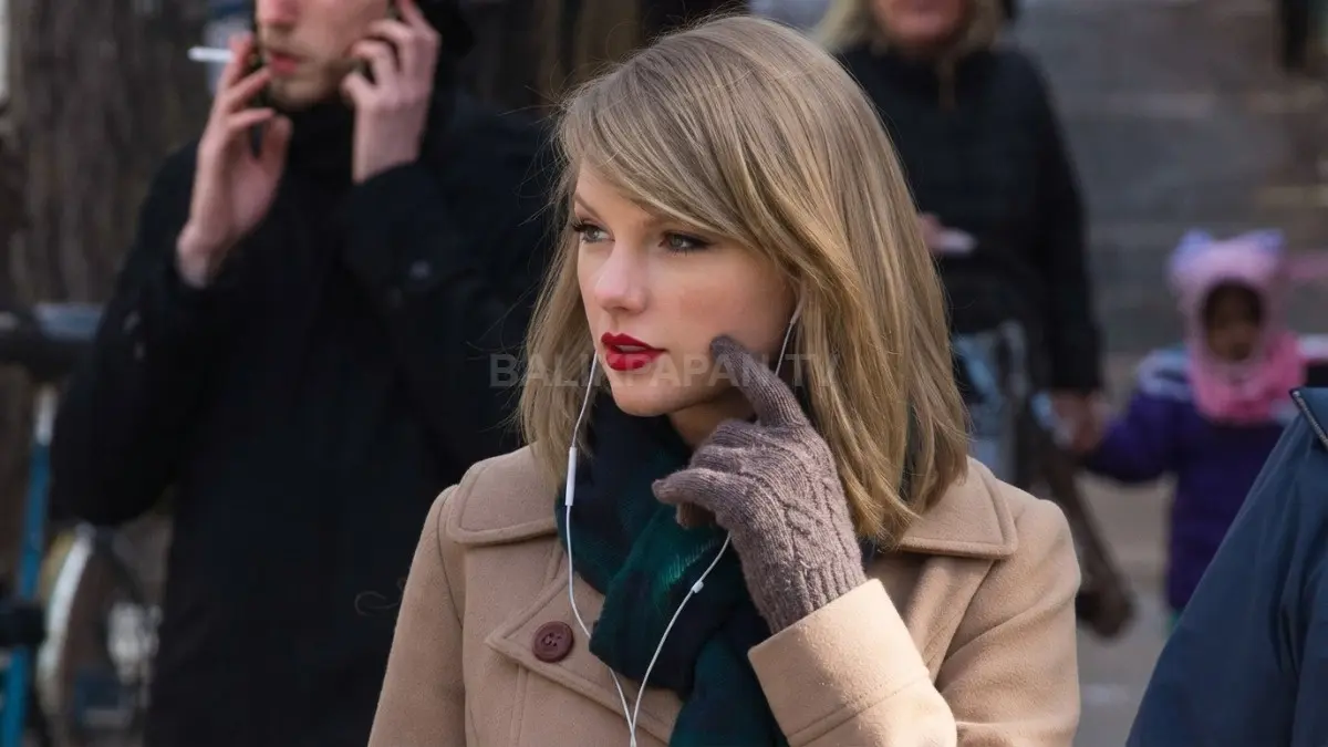 Gaya kasual Taylor Swift dalam balutan mantel cokelat dan sarung tangan rajut saat menikmati suasana di luar ruangan. (BTV/Ai)